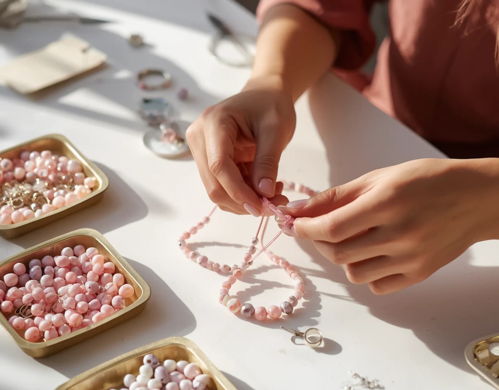 Jewelry maker threading pink beads at her worktable